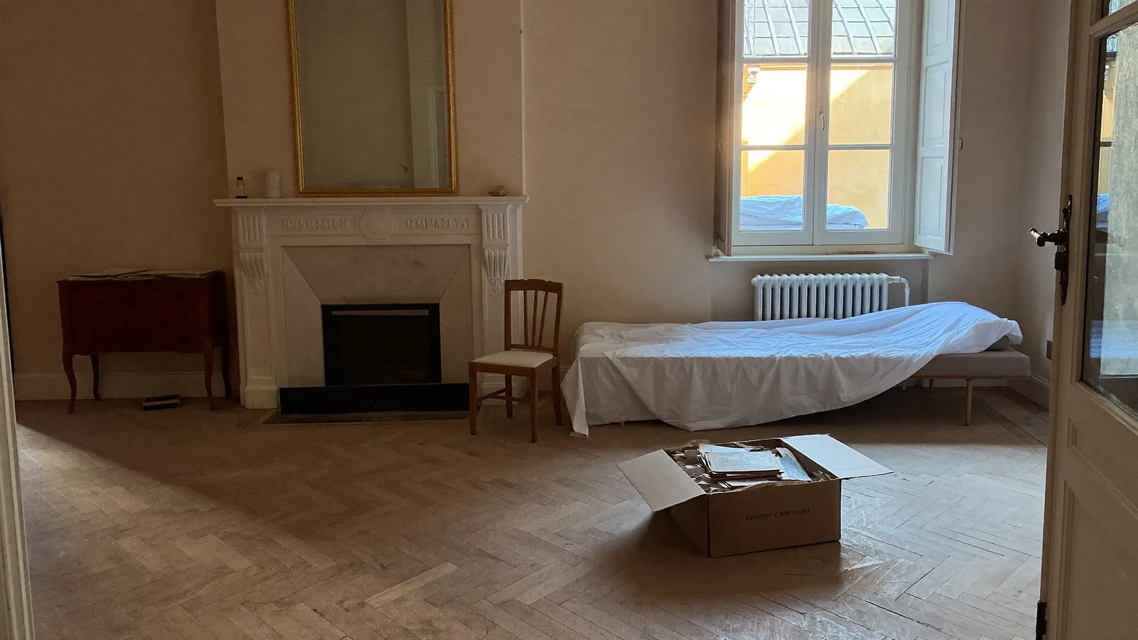 Salon d'un appartement de famille lyonnais hérité, meubles couverts de draps blancs et parquet ancien